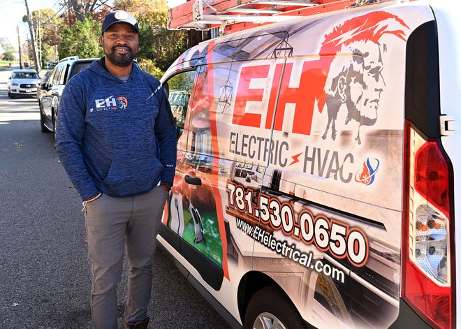 Edson Hilaire, owner EH Electric & HVAC in Waltham, stands in front of his truck at a job site on Wentworth Street in Dedham, Nov. 9, 2022.  
