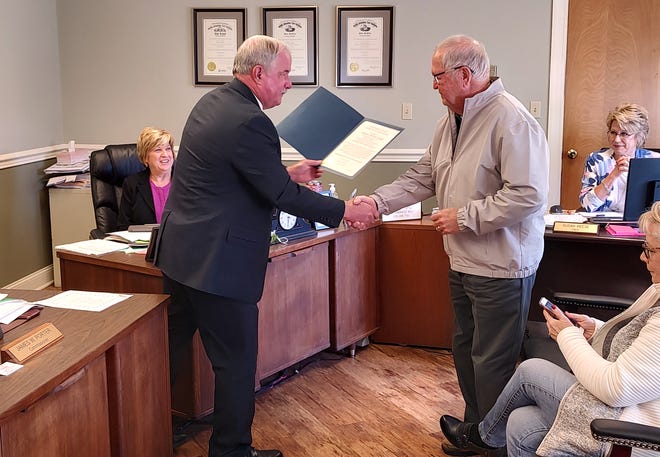 Muskingum County Commissioner Jim Porter shakes hands with Captain Bill Page after reading a proclamation in Page's honor recently. Page retired as the captain of the Lorena after 18 years.