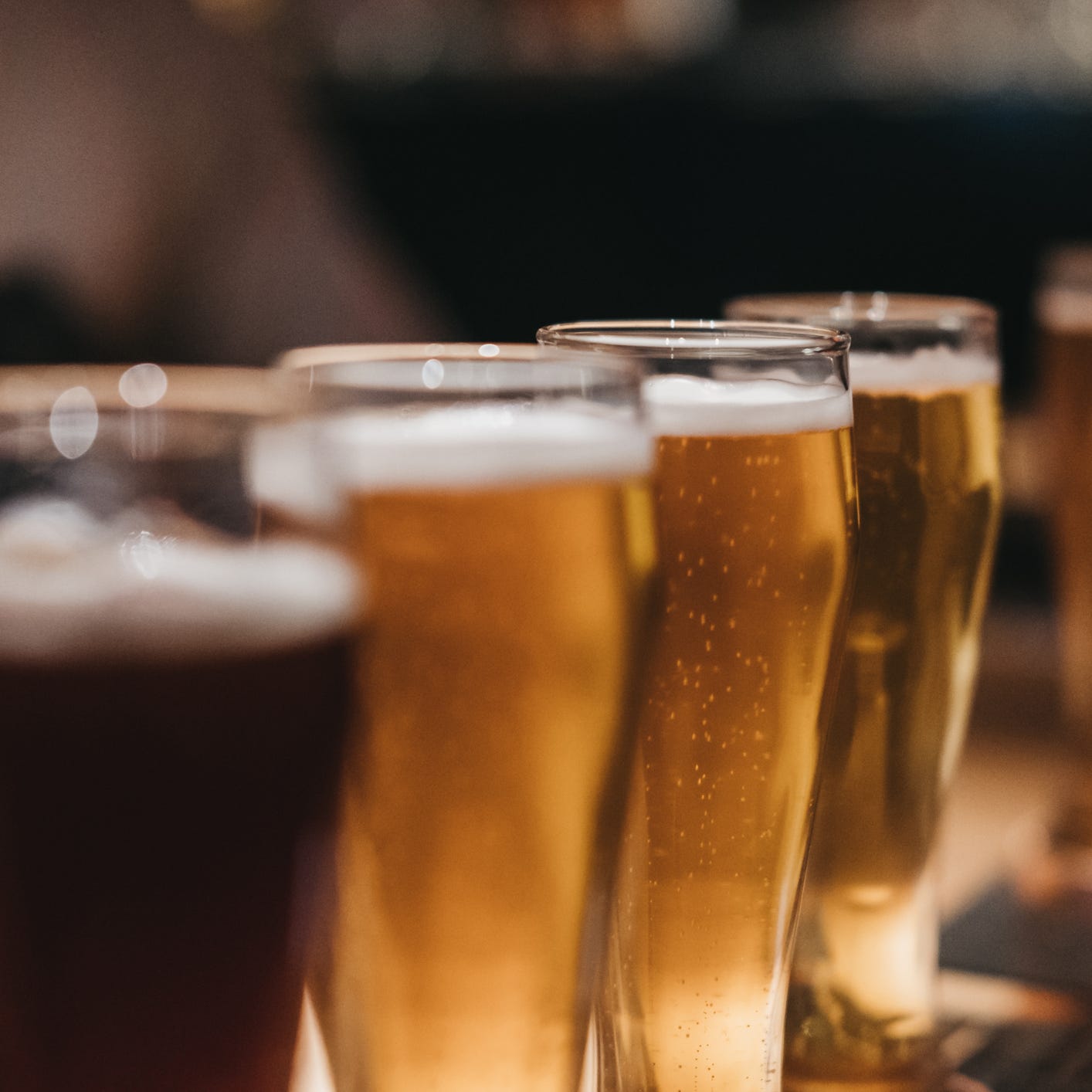 Close up of a rack of different kinds of beers, dark to light, on a table. Selective focus.