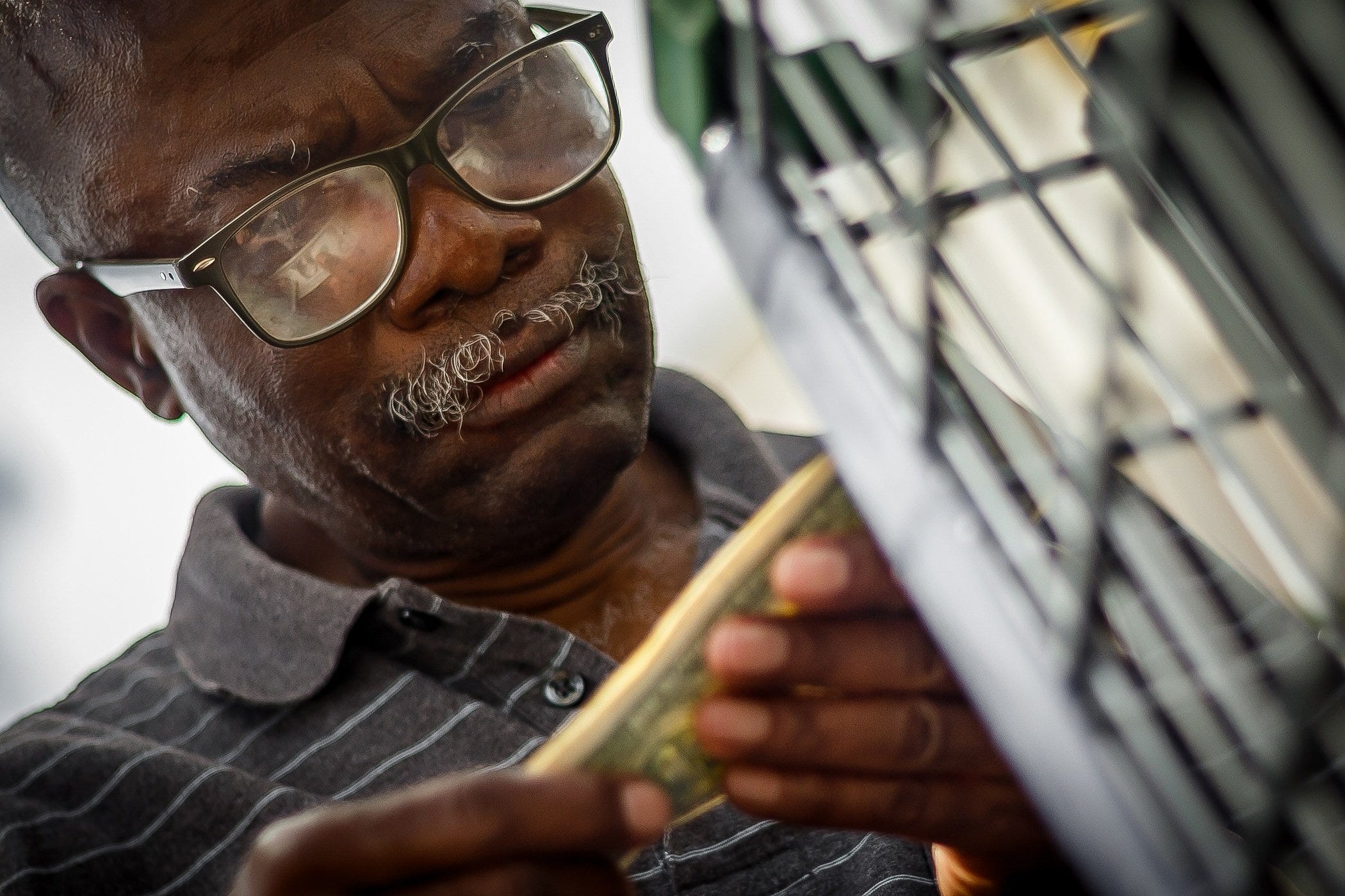 Degraff Jean methodically checks his currency to ensure he is giving the correct bills to a PalmTran driver before he is picked up at a local supermarket in West Palm Beach. DeGraff is losing his eyesight due to glaucoma.