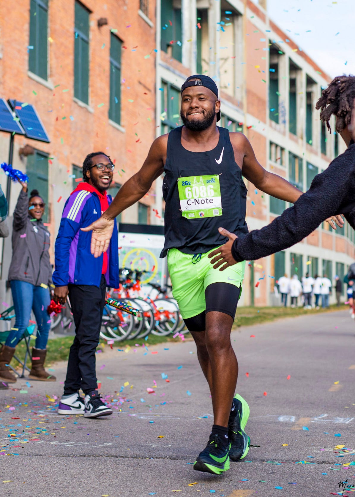 WeRun313 co-founder Lance Woods (left) and others cheer on Colby White, of Novi (Bib Number 6086) as White runs through the Dequindre Cut around the 18-mile mark of the Detroit Free Press Marathon on Oct. 16th, 2022.