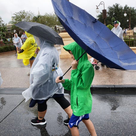 Winds blow an umbrella inside-out as guests leave the Magic Kingdom at Walt Disney World in Lake Buena Vista, Fla., Wednesday, Nov. 9, 2022, as conditions deteriorate with the approach of Hurricane Nicole. All 4 Disney parks in Central Florida closed early Wednesday because of the impending storm.
