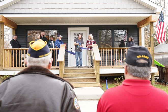 New homeowner Joshua Traeger, a U.S. Air Force veteran, cuts the ribbon during Habitat for Humanity of Lenawee County's home dedication ceremony Friday, Nov. 11, 2022, in Adrian. Habitat built the house with the intent of having it go to a veteran.