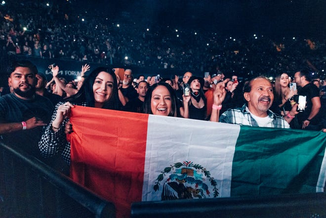 Los fanáticos sostienen la bandera mexicana en un concierto en Los Ángeles para Maná.