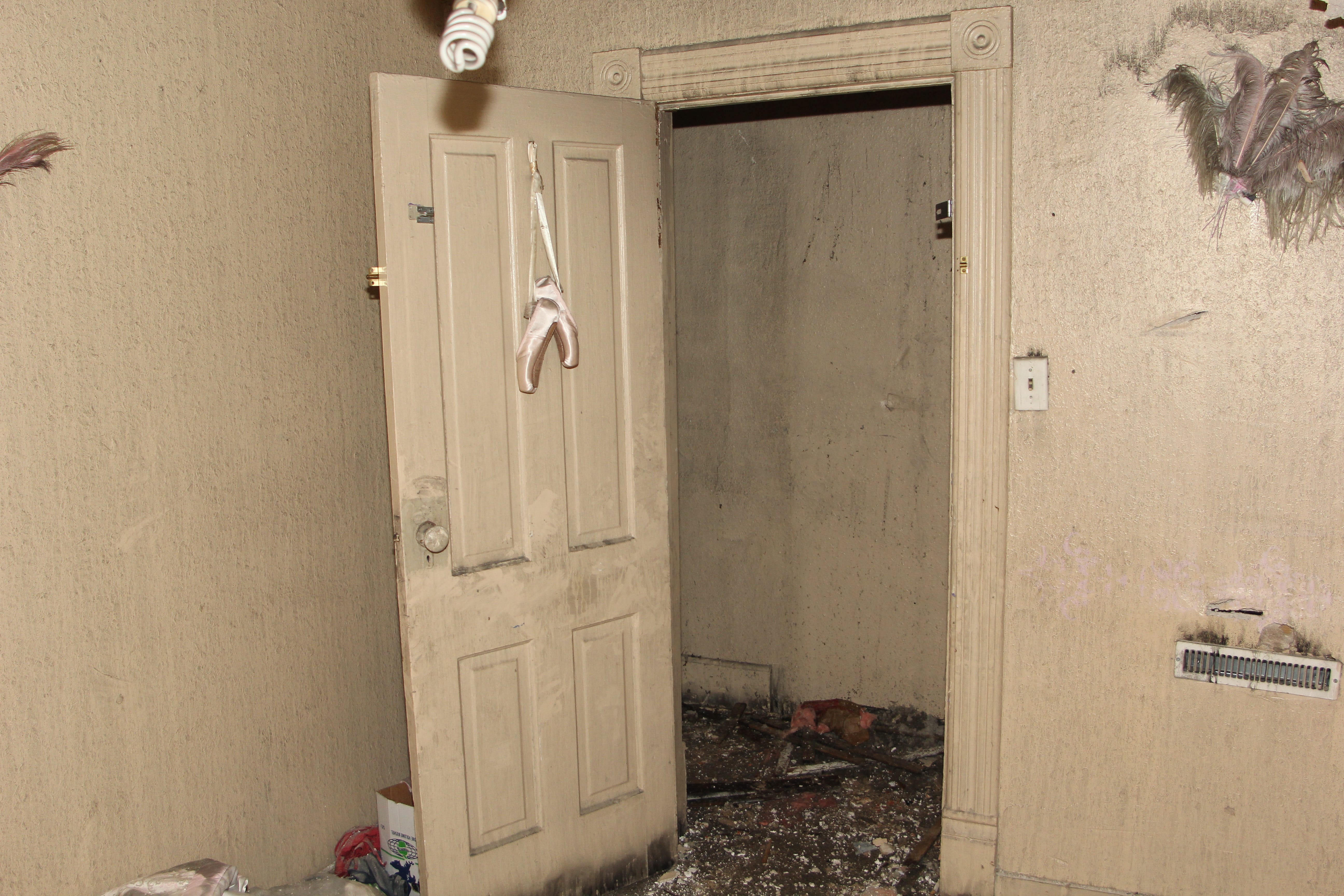 After the fire, ballet slippers hang from a door.