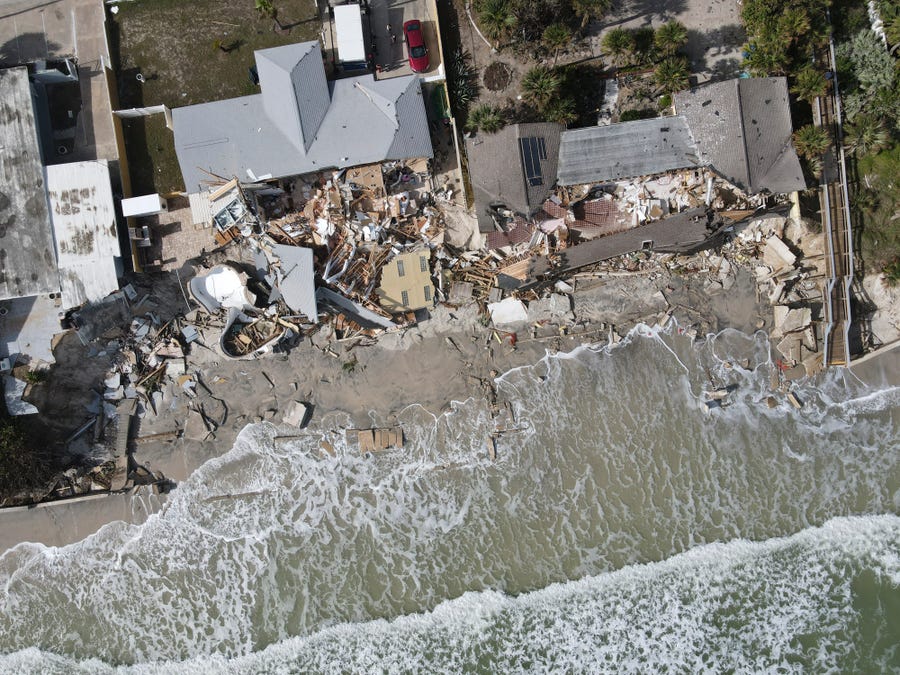 Waves lap the eroded beach below the half-collapsed homes of Nina Lavigna, at left, and her neighbor, after Hurricane Nicole swept away sand from the beach and from under foundations, Saturday, Nov. 12, 2022, in Wilbur-By-The-Sea, Florida.