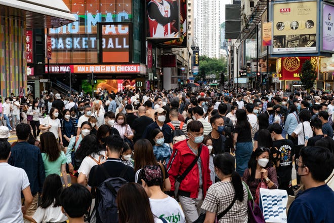 Residents cross an intersection at a shopping district on October 30, 2022 in Hong Kong, China.