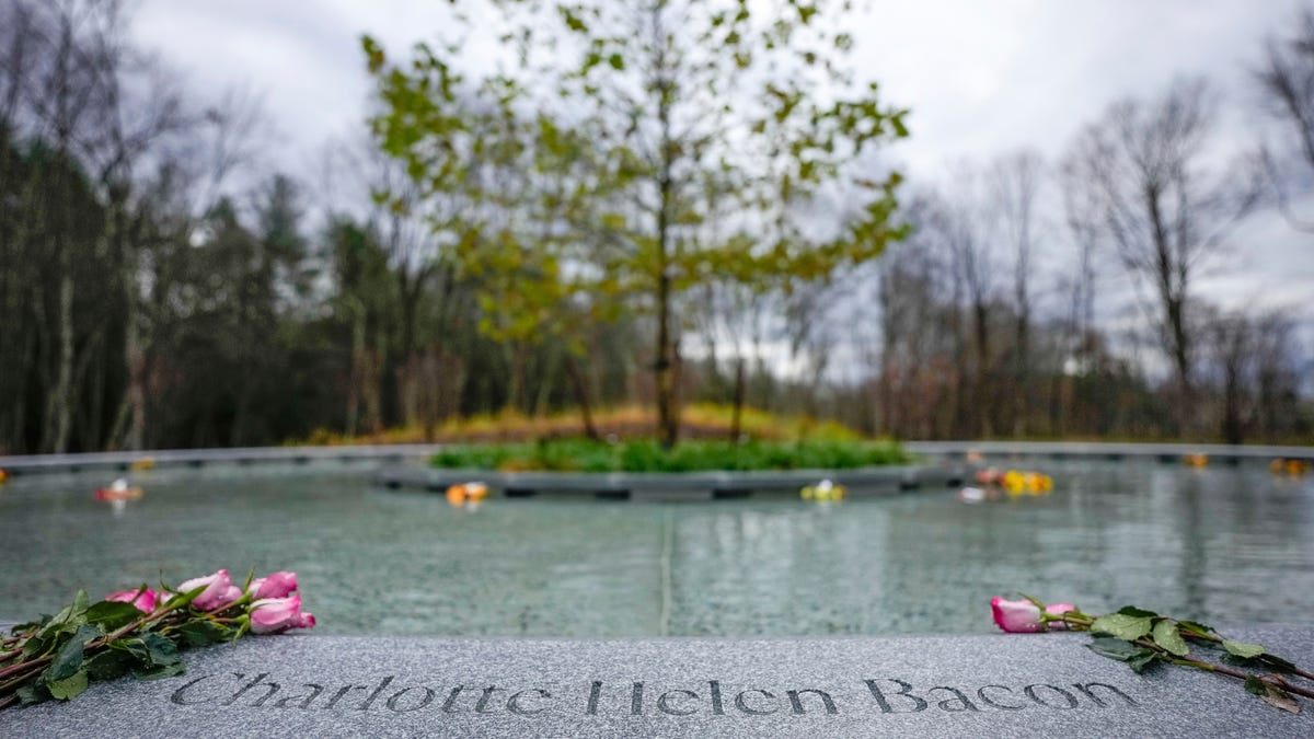 Flowers lay next to the name of Charlotte Bacon, carved in the stone of a memorial dedicated to the victims of the Sandy Hook Elementary School shooting, in Newtown, Conn., Sunday, Nov. 13, 2022. (AP Photo/Bryan Woolston)