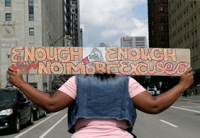 A woman carries a sign as Mothers of Murdered Columbus Children marched up West Broad Street during an anti-gun violence event at Columbus City Hall on Aug. 1, 2021.