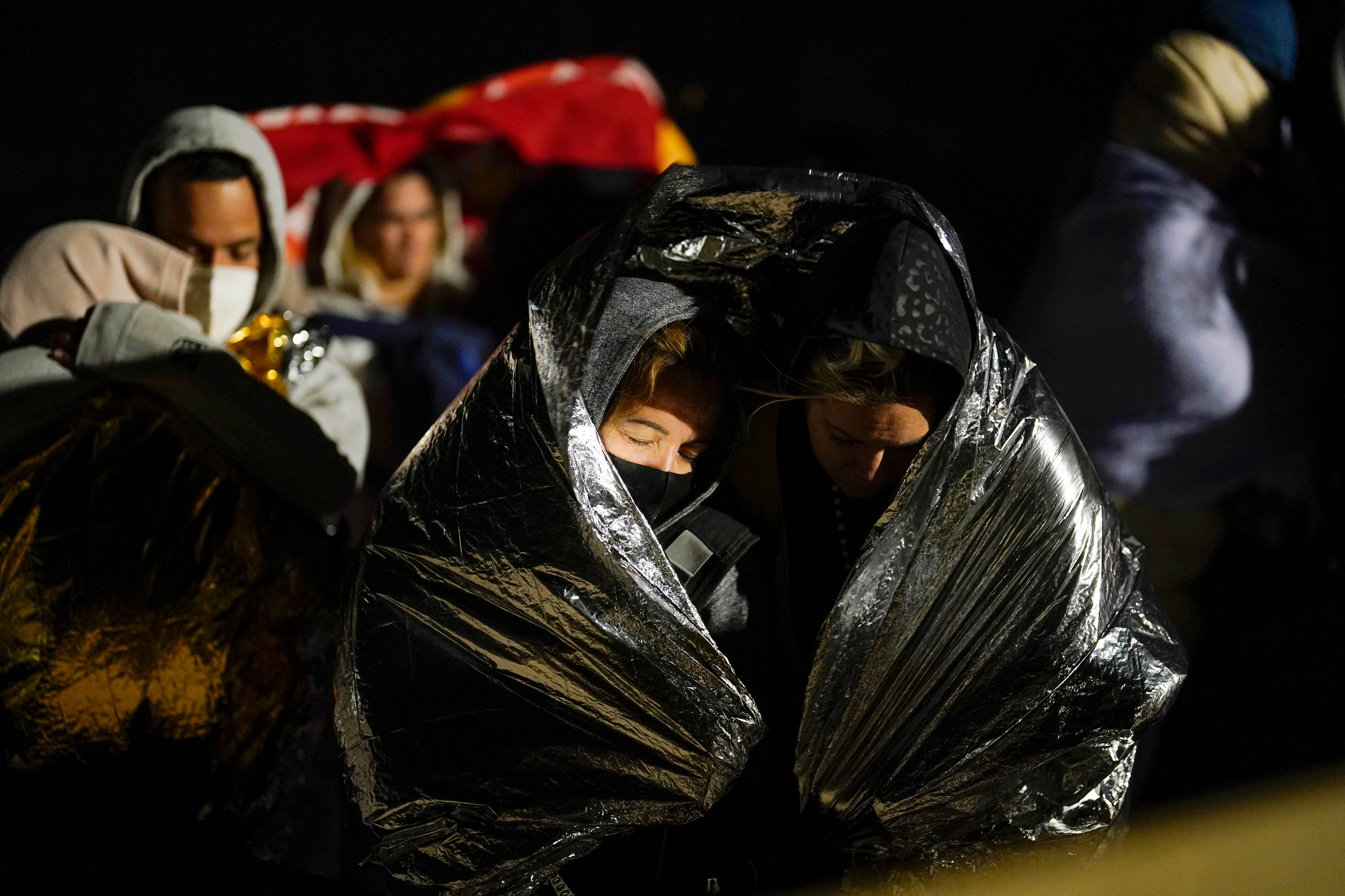 Two women from Cuba try to keep warm after crossing the border from Mexico and surrendering to authorities to apply for asylum on Nov. 3, 2022, near Yuma.