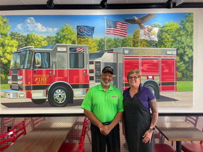 Larry Webb, franchise owner of the Firehouse Subs shop in Springfield, and district manager Mary Fleck stand in front of the restaurant's custom mural of a Springfield firetruck.
