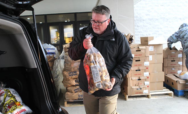 Sherwood Oaks Christian Church of Bedford Pastor Tim Thompson loads a bag of potatoes into a vehicle during the Tuesday Food Box Giveaway.