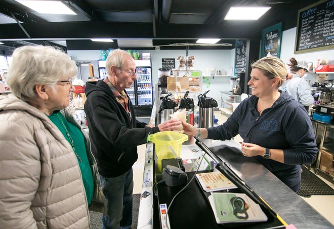 NautiMi on the River co-owner Melissa Kunnert, right, serves frequent customers Linda and Gary Locher at the Dexter Township store and watercraft launch, located on the Huron River near Portage Lake, on Wednesday, Nov. 16, 2022.