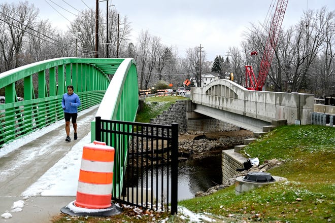 A jogger passes by the construction site of the Okemos Road bridges on Wednesday, Nov. 16, 2022, in Meridian Township.