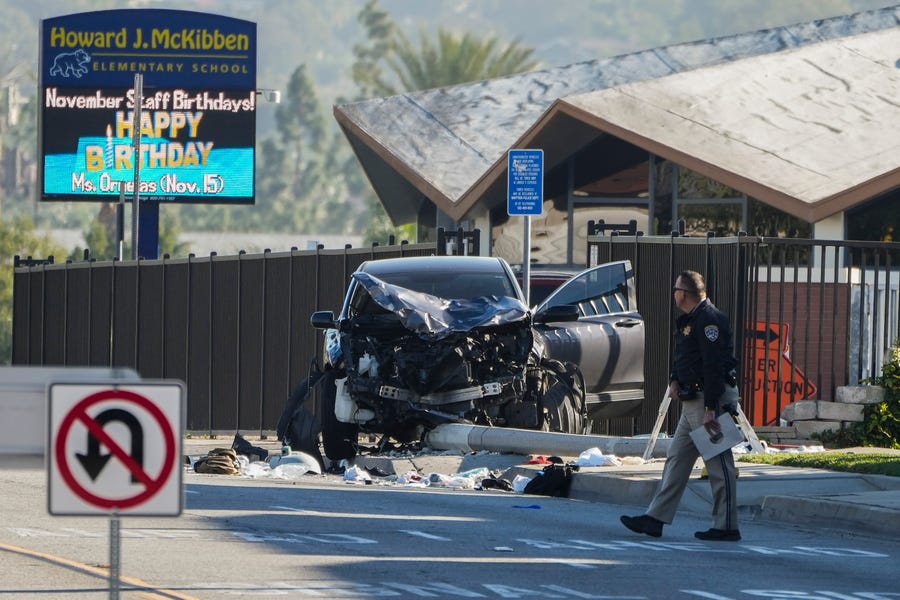 An investigator walks past a mangled SUV that struck Los Angeles County sheriff's recruits in Whittier, Calif., Wednesday, Nov. 16, 2022. The vehicle struck several Los Angeles County sheriff's recruits on a training run around dawn Wednesday, some were critically injured, authorities said.
