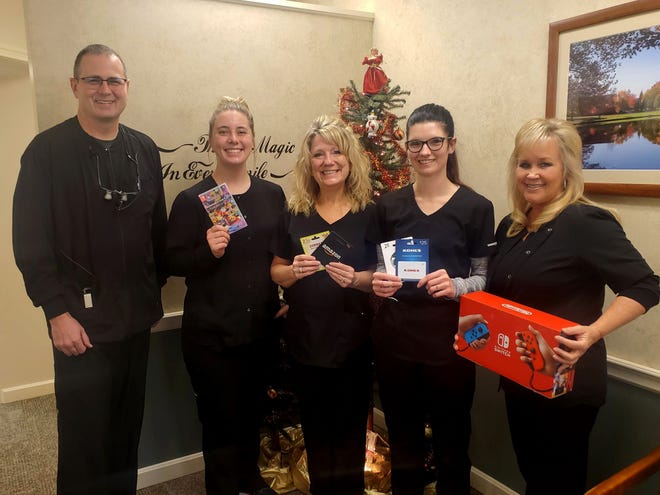 Alliance Orthodontist Dr. Michael Paulus, left, and office staff show off items that donors at a Dec. 1 blood drive could win.