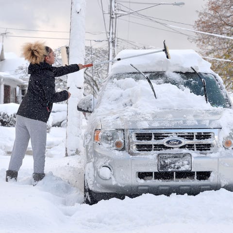 Taylor Olson clears snow from her car in Erie, Pa.