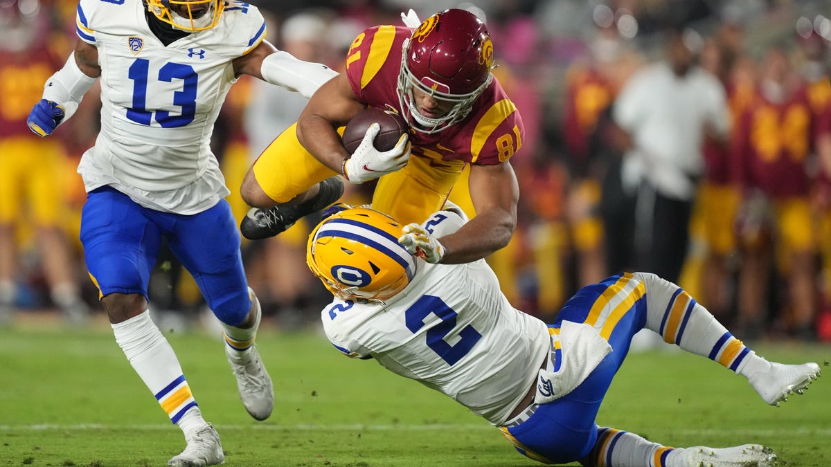 Southern California wide receiver Austin Overn (82) is tackled by California safety Miles Williams (13) and safety Craig Williams in the first half at United Airlines Field at Los Angeles Memorial Coliseum.