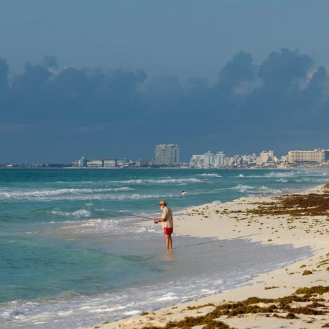 A tourist fishes from the shore in Cancun, Mexico,