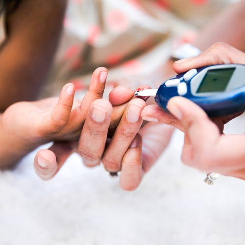 Mother is checking her daughters' diabetes by moni
