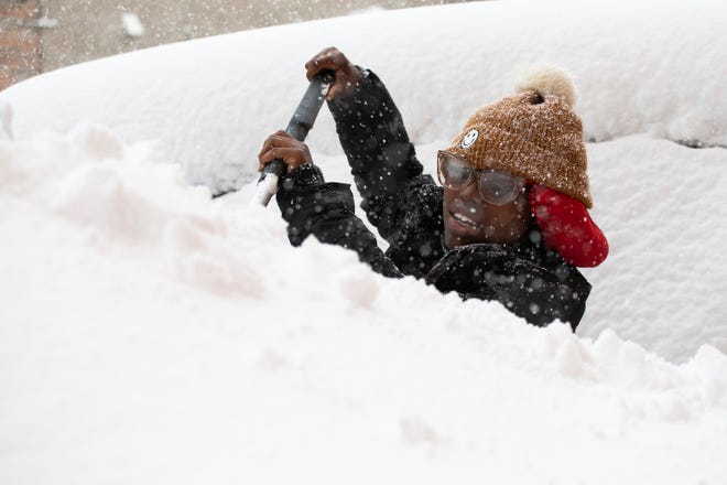 Zaria Black, 24, clears off her car as snow falls Friday, Nov. 18, 2022, in Buffalo, New York.