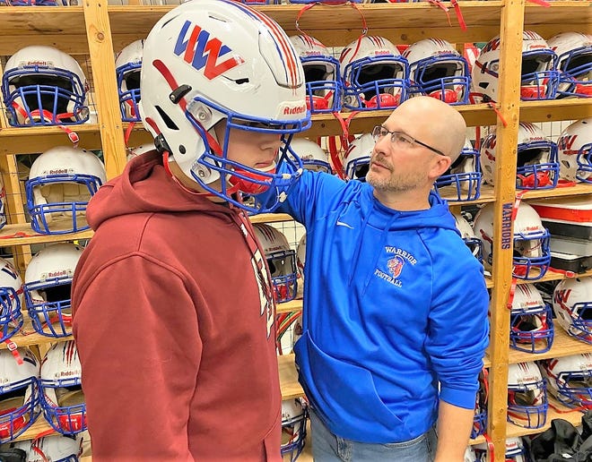 Winnacunnet High School head football coach Ryan Francoeur checks junior Kaleb Joiner's helmet Sunday, Nov. 30, 2022. The Warriors redistributed uniforms and equipment after being asked to play Lowell (Mass.) High School on Thanksgiving Day morning.
