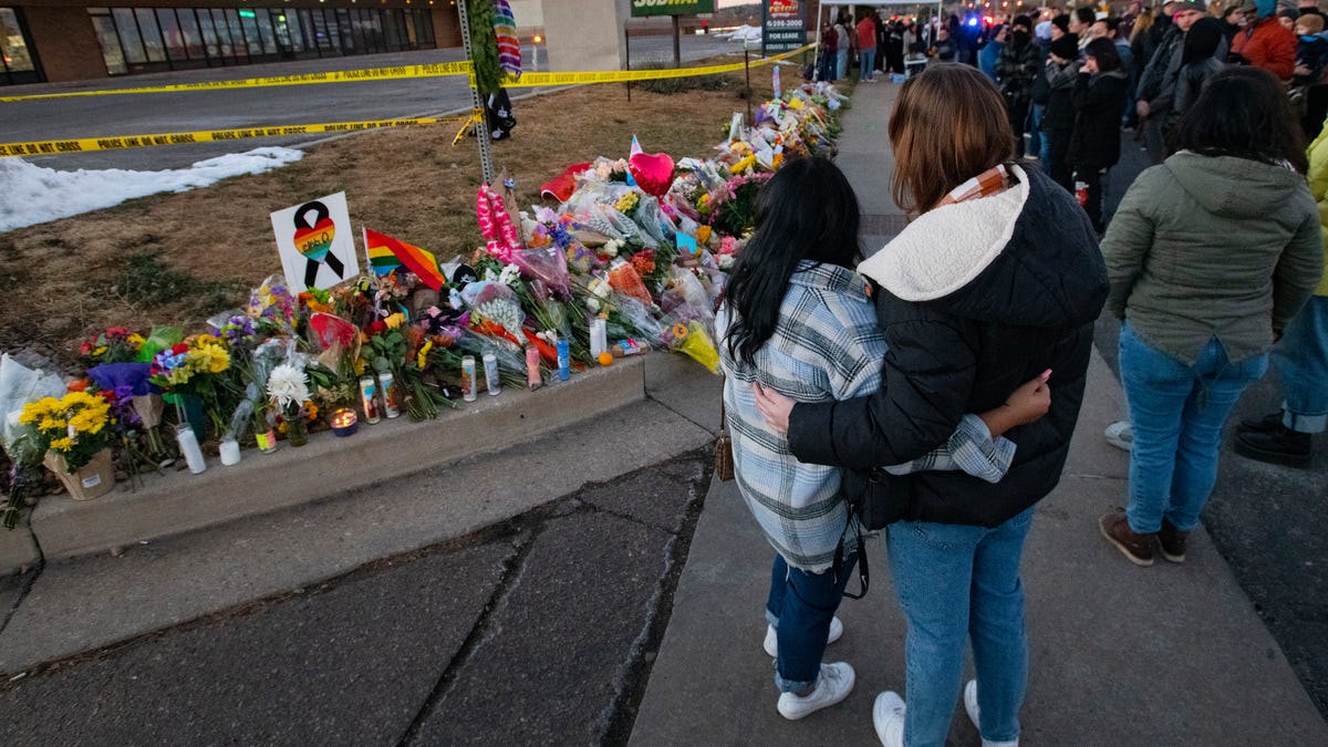 People gather around a memorial Sunday for the victims of Saturday's fatal shooting at Club Q in Colorado Springs, Colorado