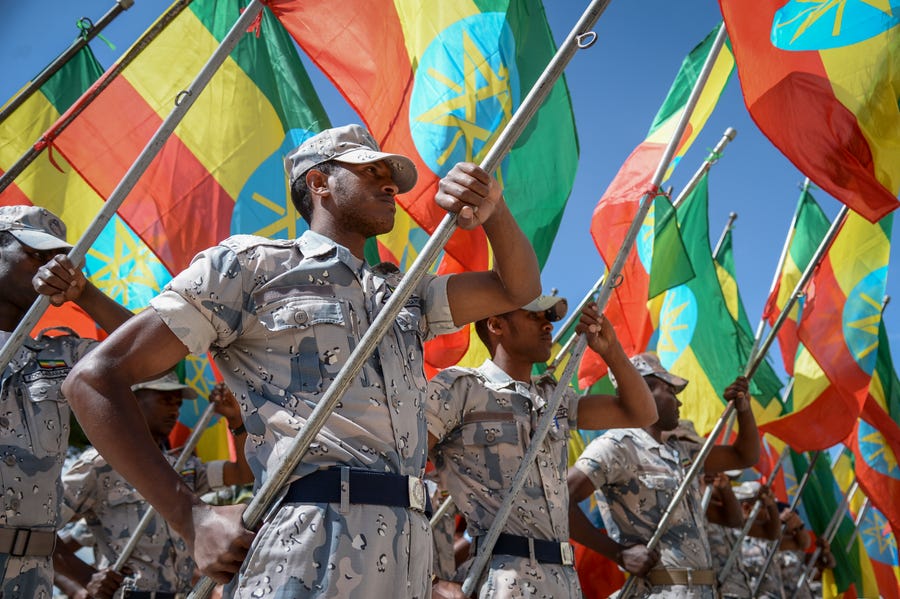Members of the Ethiopian National Defense Force hold national flags as they parade during a ceremony to remember those soldiers who died on the first day of the Tigray conflict, outside the city administration office in Addis Ababa, Ethiopia, Nov. 3, 2022.