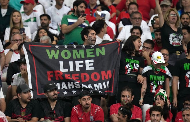 Een Iraanse fan leest een spandoek "Het leven van vrouwen Vrijheid Masha Amini" Voor de WK-wedstrijd tussen Engeland en Iran in het Khalifa International Stadium in Doha, Qatar op 21 november 2022.