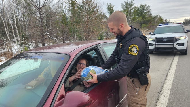 Cheboygan County Deputy Neil Simmons hands out a turkey to a lucky driver.