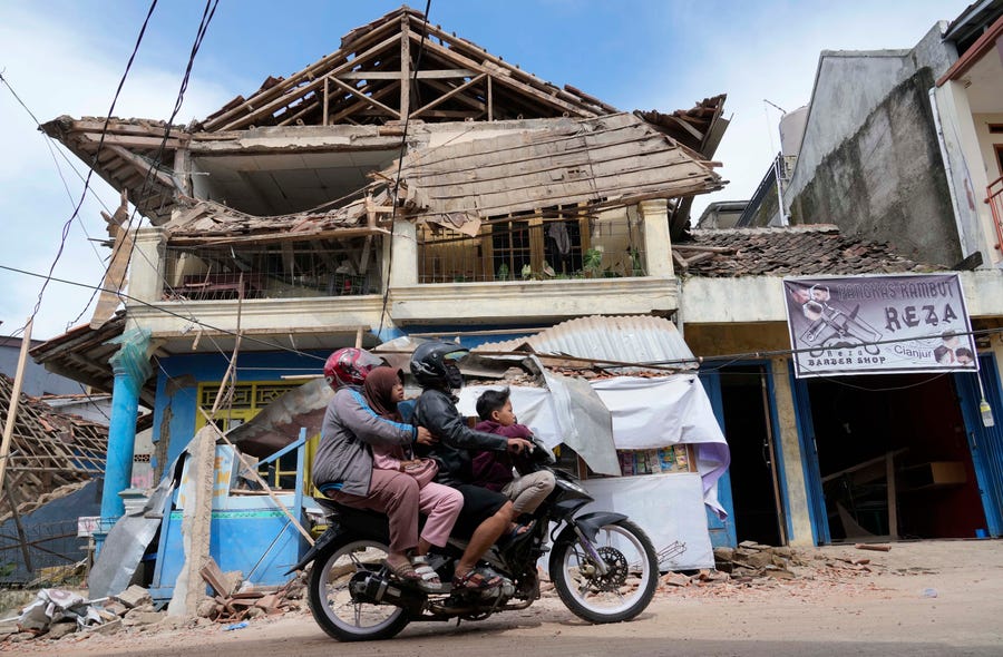 People ride a motorbike past a building damaged in Monday's earthquake in Cianjur, West Java, Indonesia, Tuesday, Nov. 22, 2022.