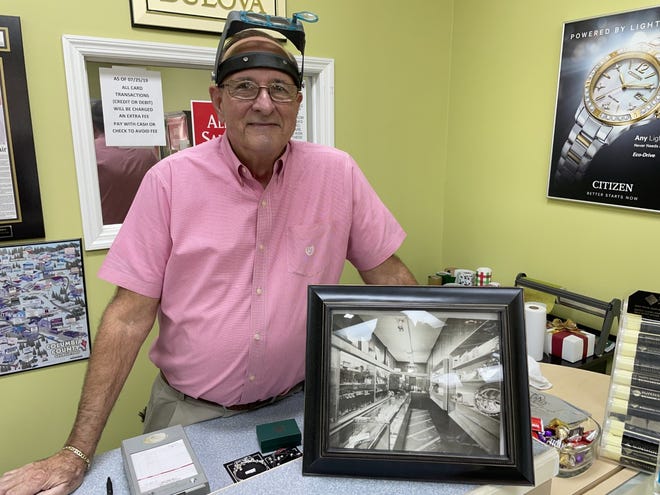 Joe Casella, owner of Casella Jewelers in Martinez, stands next to an undated photo showing his father, Leonard Casella, posing at the counter of Casella Jewelers when it was at 755 Broad St. in downtown Augusta for about 30 years.