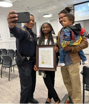 Laurinburg Police Chief Mitch Johnson snaps a photo with Kaliyah Harrington, center, two members of her family. Kaliyah helped save her family from a house fire on Oct. 29.