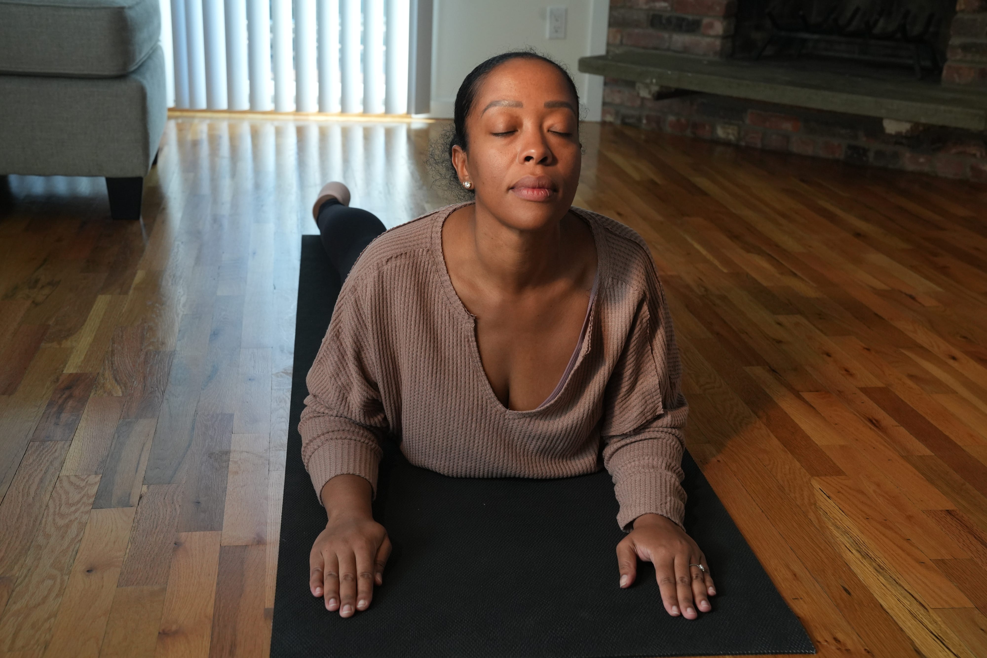 Patricia Lafontant manages her years of lower back pain by stretching several times a week, as well as massage therapy. She does some of her stretches in her Port Washington, NY home prior to her shift as an operating room nurse on November 22, 2022.