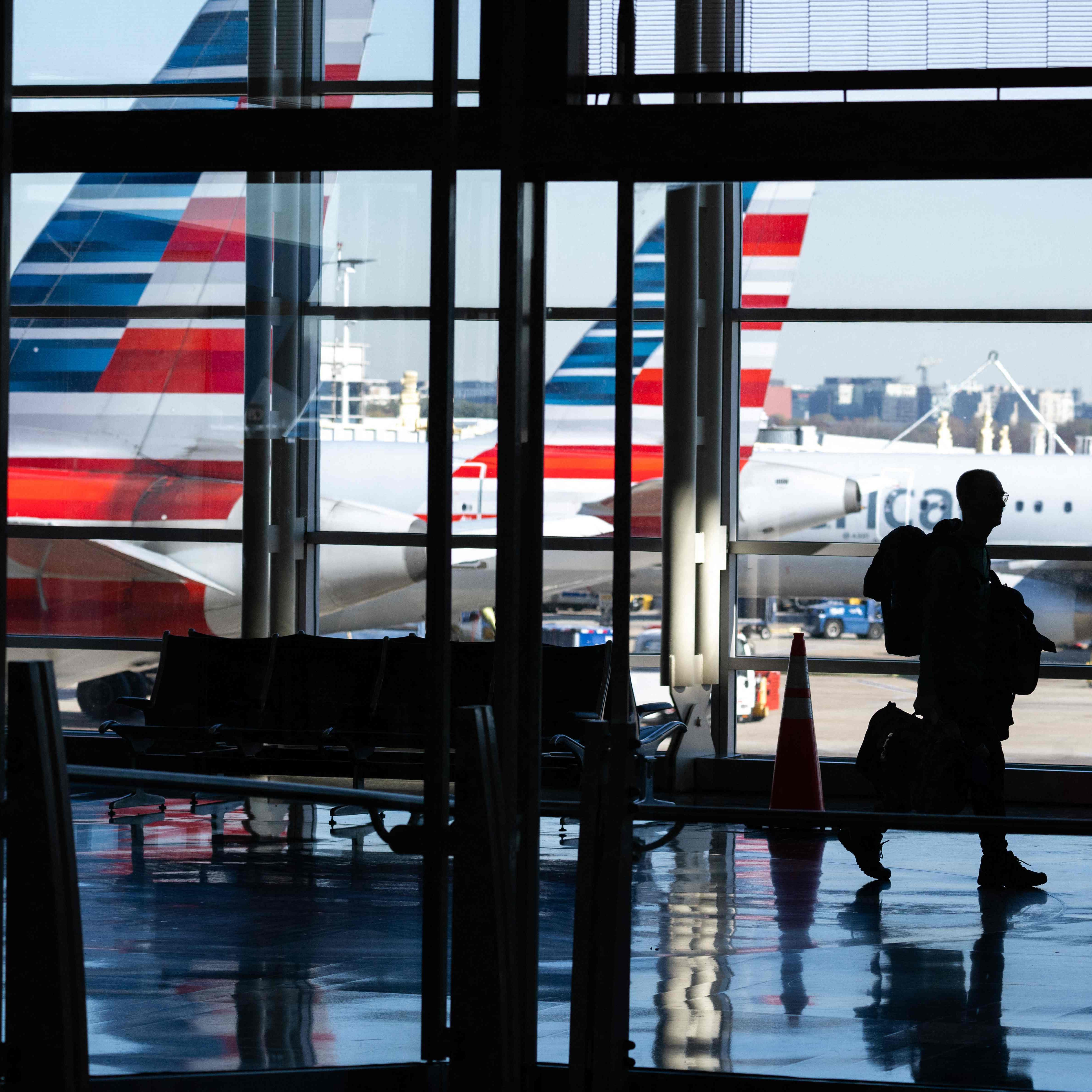 American Airlines airplanes are seen past a traveler walking through Ronald Reagan Washington National Airport in Arlington, Virginia, on November 22, 2022, ahead of the upcoming Thanksgiving holiday. 