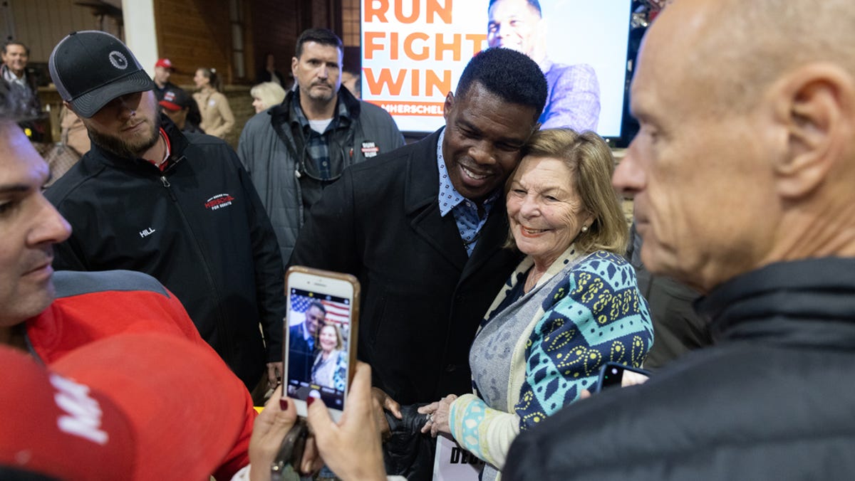 Republican Senate nominee Herschel Walker takes a photo with a supporter during a rally on November 21, 2022 in Milton, Georgia. Walker faces incumbent Sen. Raphael Warnock, D-Ga., in a runoff election on December 6th.