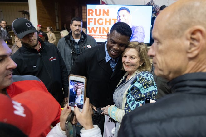 Republican Senate nominee Herschel Walker takes a photo with a supporter during a rally on November 21, 2022 in Milton, Georgia. Walker faces incumbent Sen. Raphael Warnock, D-Ga., in a runoff election on December 6th.
