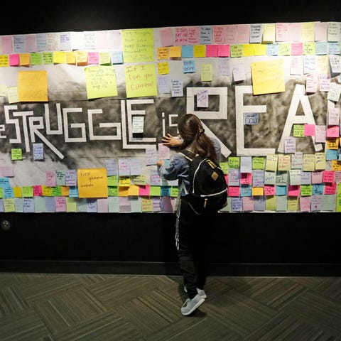 A student attaches a note to the Resilience Projec