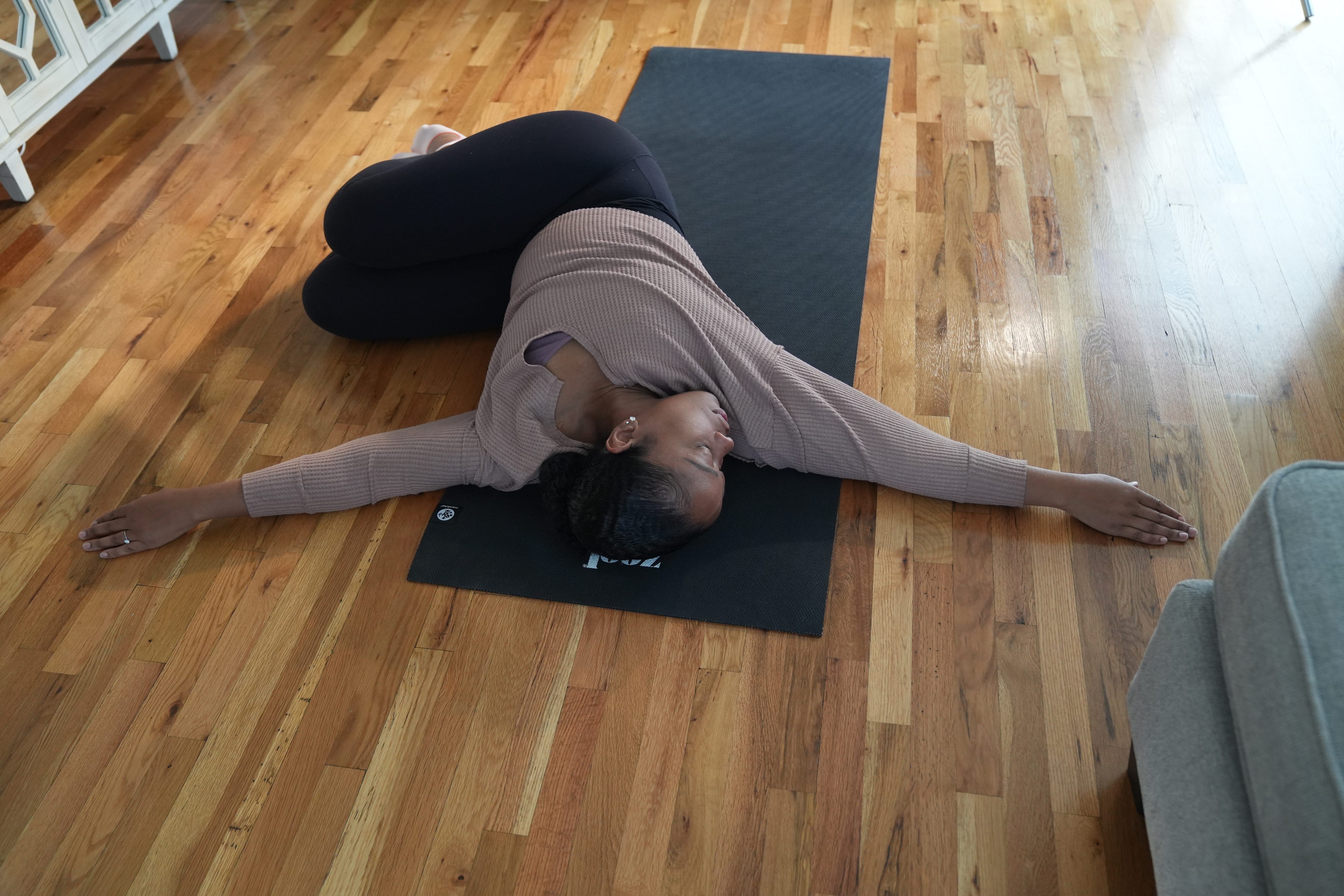 Patricia Lafontant manages her years of lower back pain by stretching several times a week, as well as massage therapy. She does some of her stretches in her Port Washington, NY home prior to her shift as an operating room nurse on November 22, 2022.