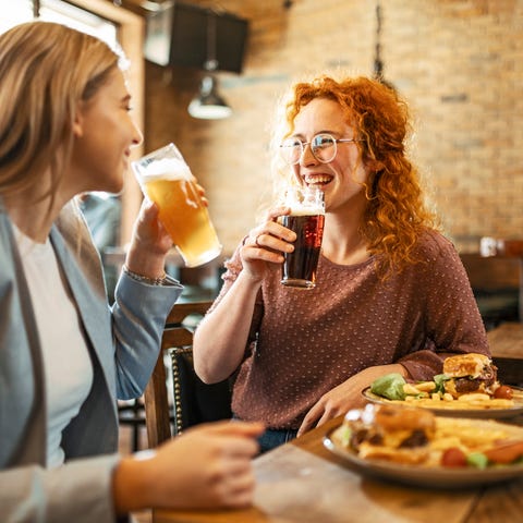 Happy Female Friends Having meal And Beer And Laug