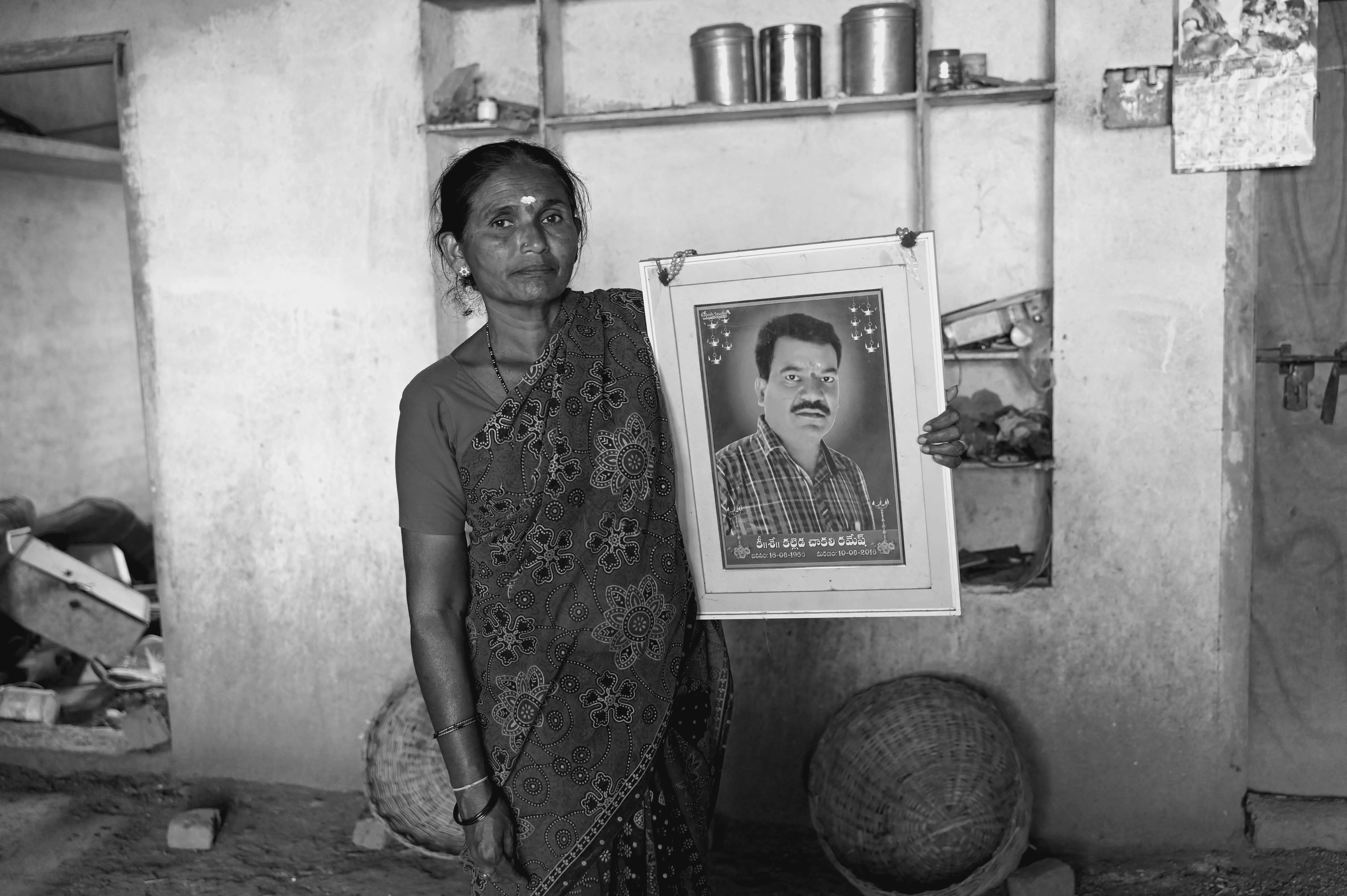 Kalleda Vinoda holds a portrait of her late husband, Ramesh, who died while working construction in Qatar. This photo was taken Nov. 11, days before the World Cup began, at her home in Velmal village of Nizamabad district in Telangana, India.