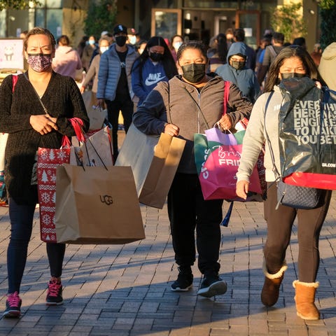 Black Friday shoppers wearing face masks carry bag