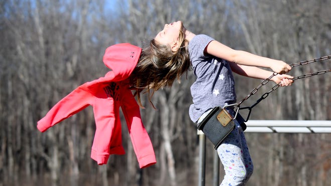 Louisa Smith, 7, of Canton loses her coat swinging as she takes advantage of the warm November weather on a trip to Quail Hollow Park in Hartville.