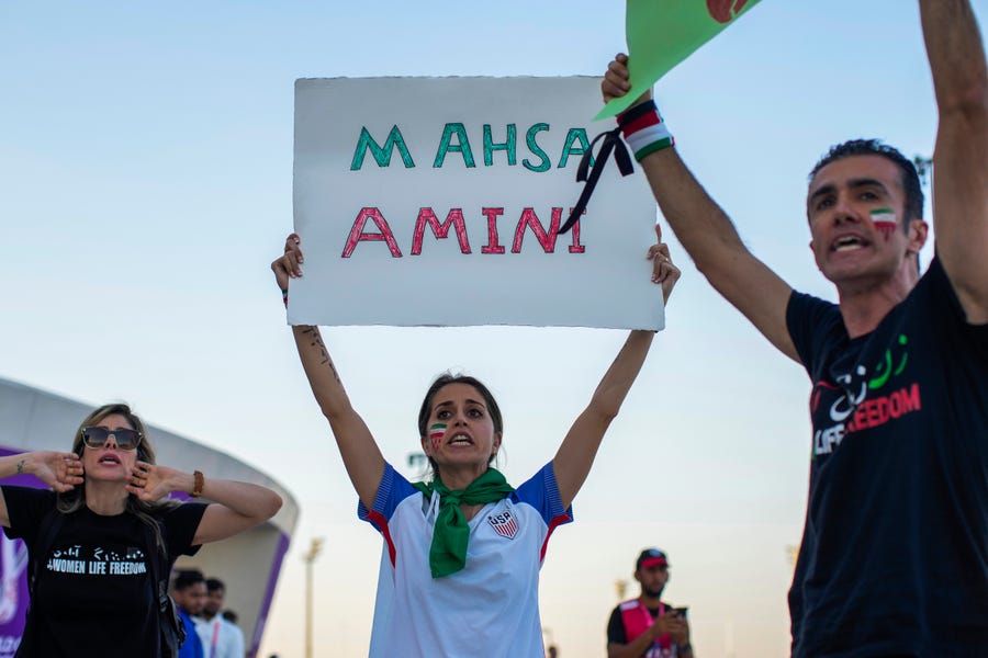 A woman holds up a sign reading Mahsa Amini, the name of a woman who died while in police custody in Iran at the age of 22, during a protest after the World Cup Group B soccer match between Wales and Iran.