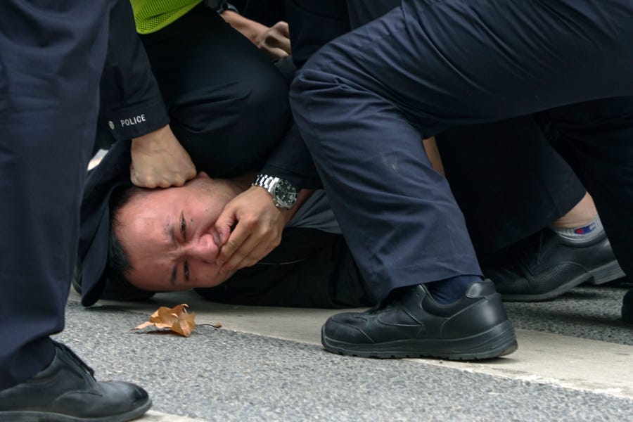 Policemen pin down and arrest a protester during a protest on a street in Shanghai, China, on Nov. 27, 2022,