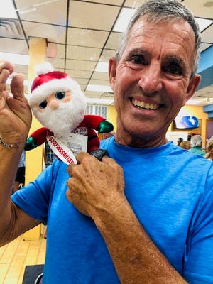 George Trosset Sr., founder of Surfing Santas, shows off what he calls "Stowaway Santa," which traveled into space Aug. 4 aboard a Blue Origin flight with local restaurant owner Steve Young.