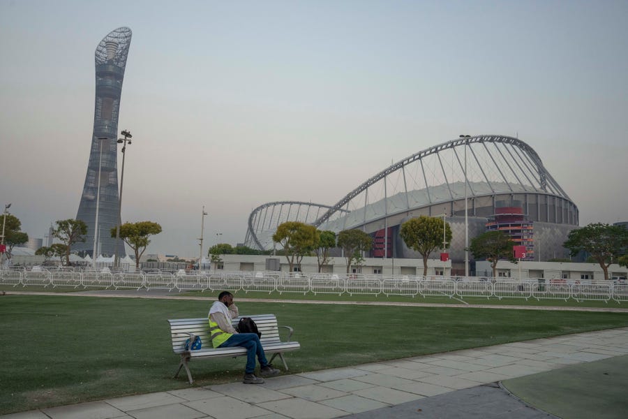A migrant worker sleeps on a bench before his early morning shift, in front of Khalifa International Stadium, which will host matches during FIFA World Cup 2022, in Doha, Qatar, Saturday, Oct. 15, 2022.