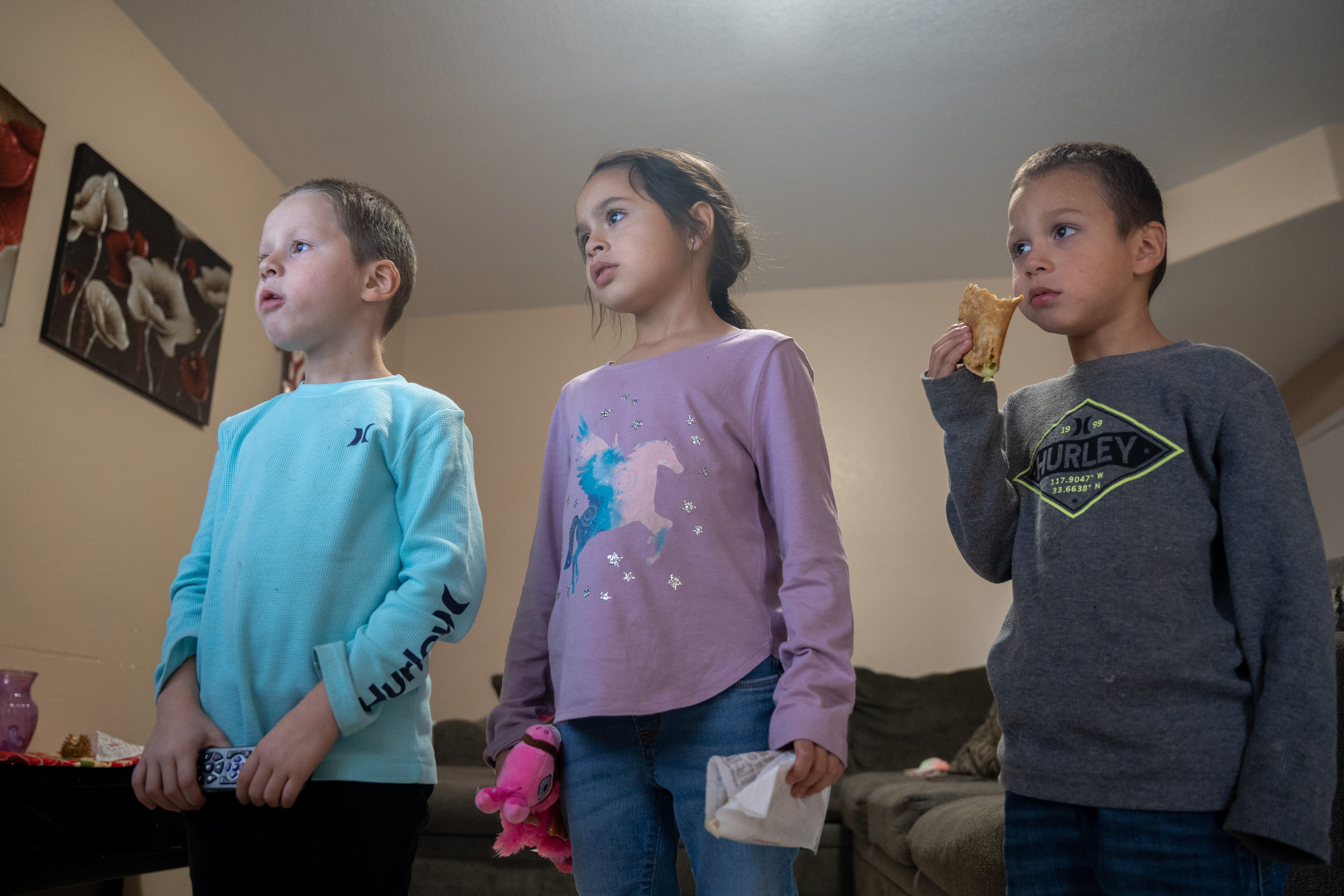 Avier, Alvira, and Adriel Arvizo eat tacos and watch television at their temporary Avondale home on Nov. 18, 2022.