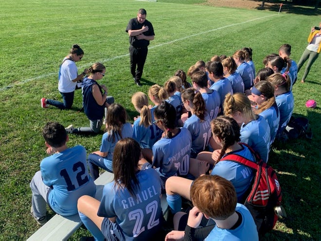 Members of the Our Lady of the Cross co-ed soccer team take part in a prayer and blessing before a game in the fall. The school, which opened in 2021, is working to add sports to its roster. Basketball will be offered in the winter.
