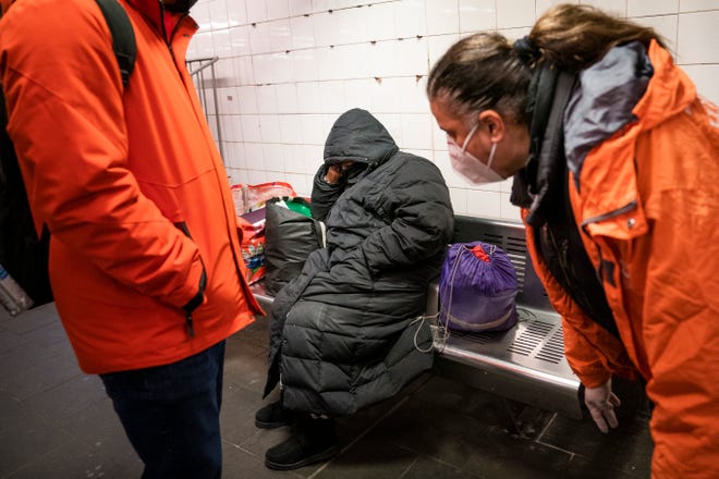 Homeless Outreach personnel reach out to a person sleeping on a bench in the Manhattan subway system, Monday, Feb. 21, 2022, in New York.